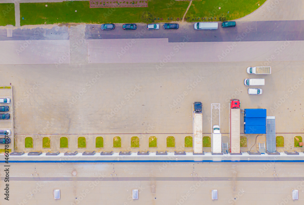 Aerial view of goods warehouse. Logistics center in industrial city zone from above. Aerial view of trucks loading at logistic center. View from drone.