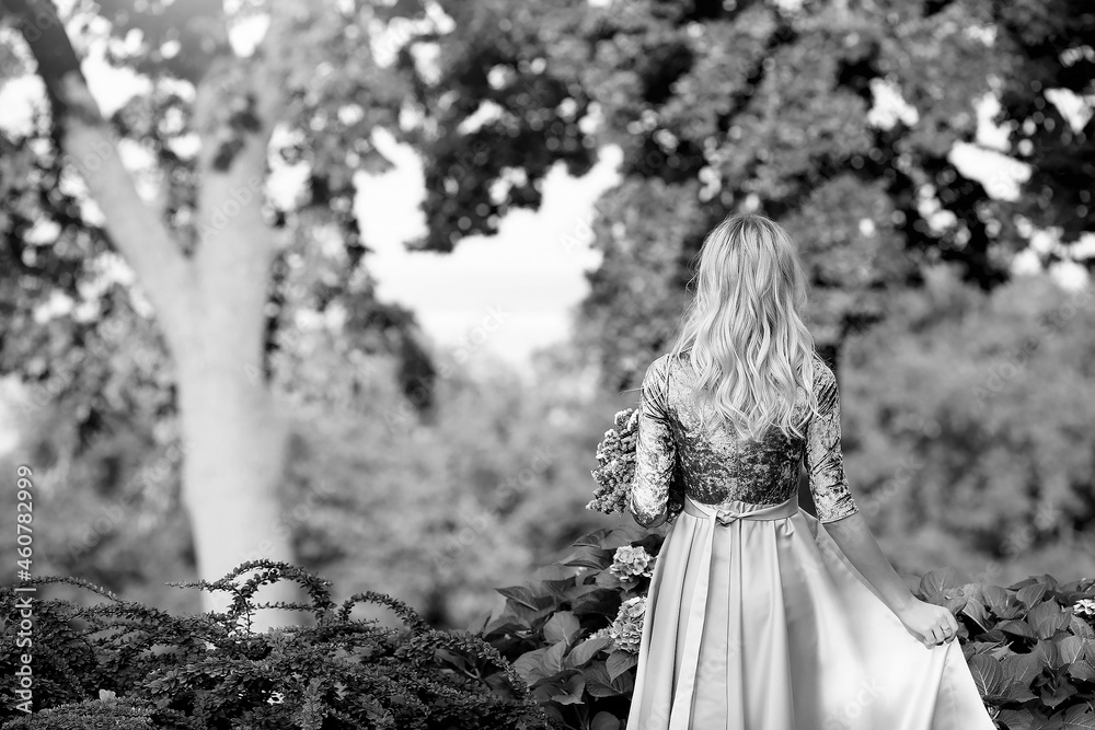 Young blonde girl standing in a gray elegant dress, view from the back, with a bouquet of pink flowers in the park. Relax. Rest in the autumn in the park. Fashion and beauty concept. Young blonde girl standing in a gray elegant dress, view from the back, with a bouquet of pink flowers in the park. Relax. Rest in the autumn in the park. Fashion and beauty concept.