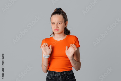 serious brunette teen girl rejecting something disgusting, wave hands in refusal, dislike smth, show cringe expression, gray background