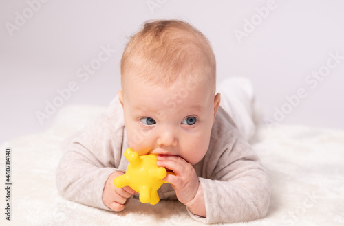 Pretty baby plays on the floor with a toy, white background