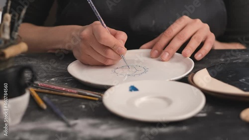 Woman hands during painting on ceramic plates. Potter workshop of making handcraft clay dishes