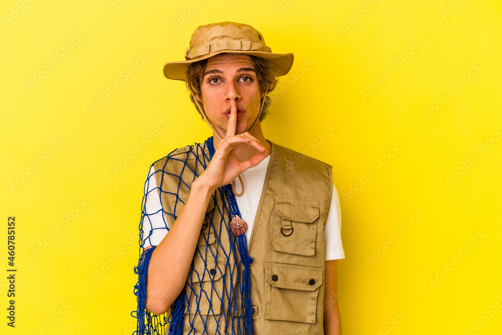 Young fisherman with makeup holding a net isolated on yellow background keeping a secret or asking for silence. Young fisherman with makeup holding a net isolated on yellow background keeping a secret or asking for silence.