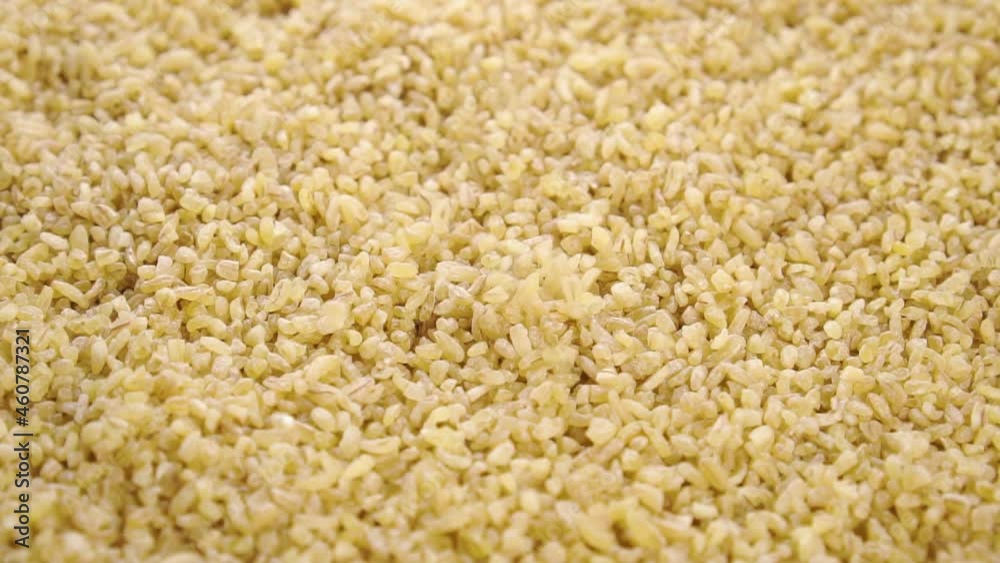 Raw bulgur groats. Falling dry crushed grains in slow motion. Macro. Vegan food concept. Rotation Raw bulgur groats. Falling dry crushed grains in slow motion. Macro. Vegan food concept. Rotation