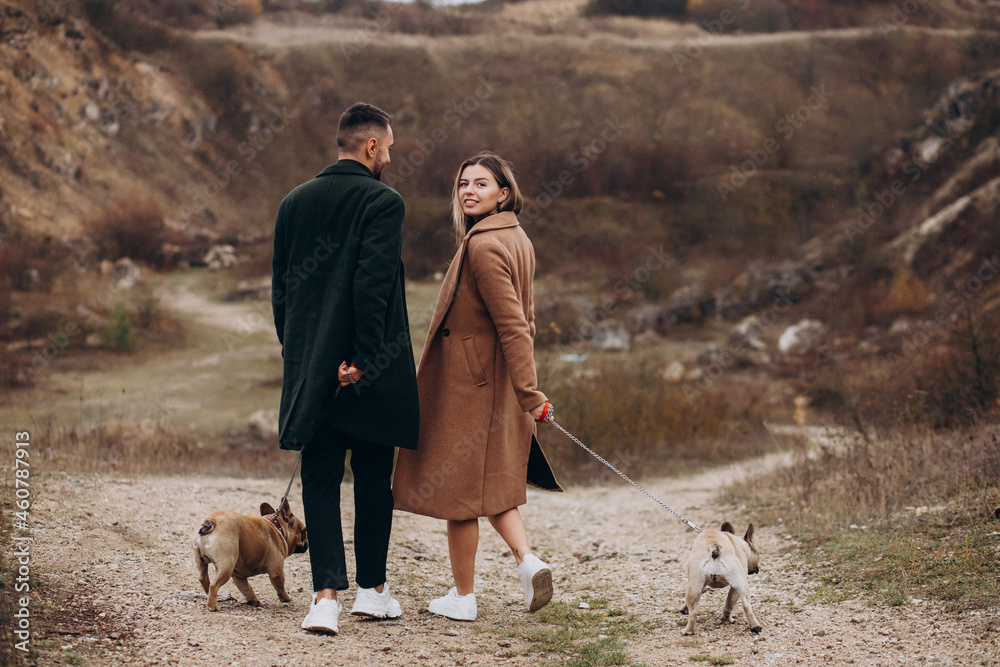 Young couple walking their french bulldogs in park