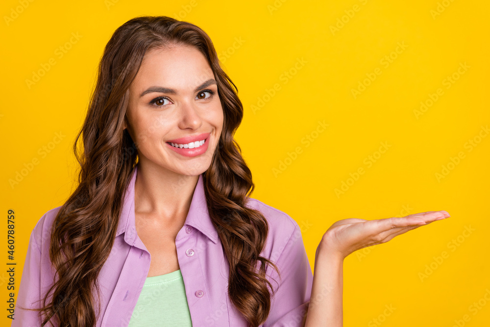 Photo portrait smiling woman keeping blank space on palm isolated bright yellow color background Photo portrait smiling woman keeping blank space on palm isolated bright yellow color background