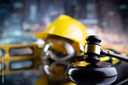 Labour law and builiding law concept.  Gavel and yellow crash helmet on the shining lawer desk. photo
