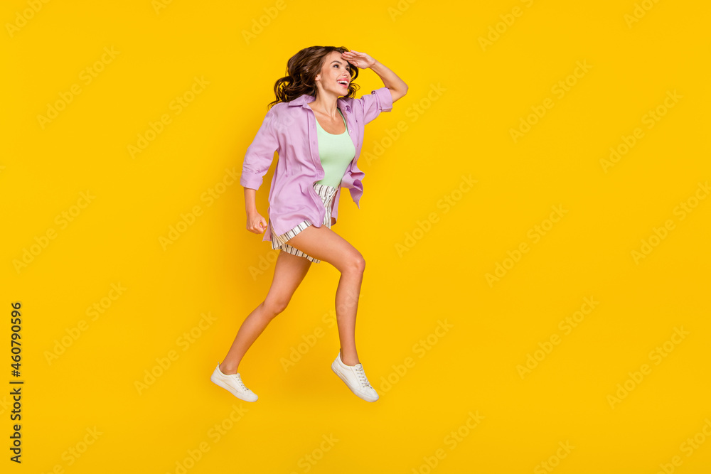 Full length photo of positive young woman jump up look empty space dream forward isolated on yellow color background Full length photo of positive young woman jump up look empty space dream forward isolated on yellow color background