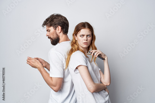 married couple in white T-shirts with phones in their hands isolated background