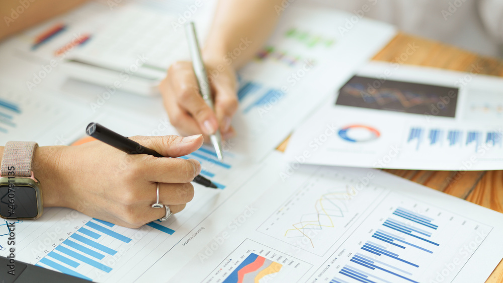Two of businesswoman analysing financial graphs and charts Two of businesswoman analysing financial graphs and charts