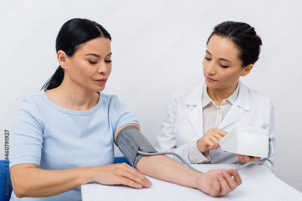 doctor in white coat measuring blood pressure of asian woman doctor in white coat measuring blood pressure of asian woman