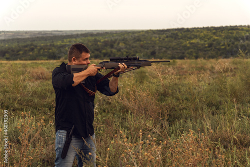 Portrait of a shooter with a rifle. European shoots a rifle with a optics sight.