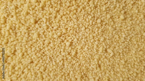 Close up of yellow golden dry couscous top view from above. Macro food us a background with copy space from above. Nutrition vegan vegetarian ingredient concept