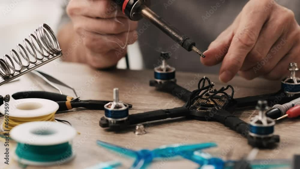 Process of quadcopter repairing using soldering iron and different tools. Closeup view Process of quadcopter repairing using soldering iron and different tools. Closeup view