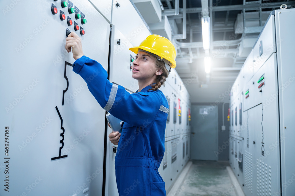 Woman Electrical Engineer working front HVAC control panels, Technician daily check solar cell controls system for security functions in service room at factory.Energy,Ventilation,Air Conditioning. Woman Electrical Engineer working front HVAC control panels, Technician daily check solar cell controls system for security functions in service room at factory.Energy,Ventilation,Air Conditioning.