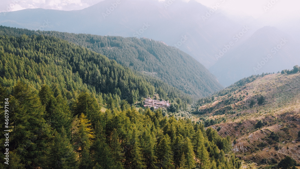 Aerial view of green fields and coniferous forest in the mountains. Italian Alps. Aerial view of green fields and coniferous forest in the mountains. Italian Alps.
