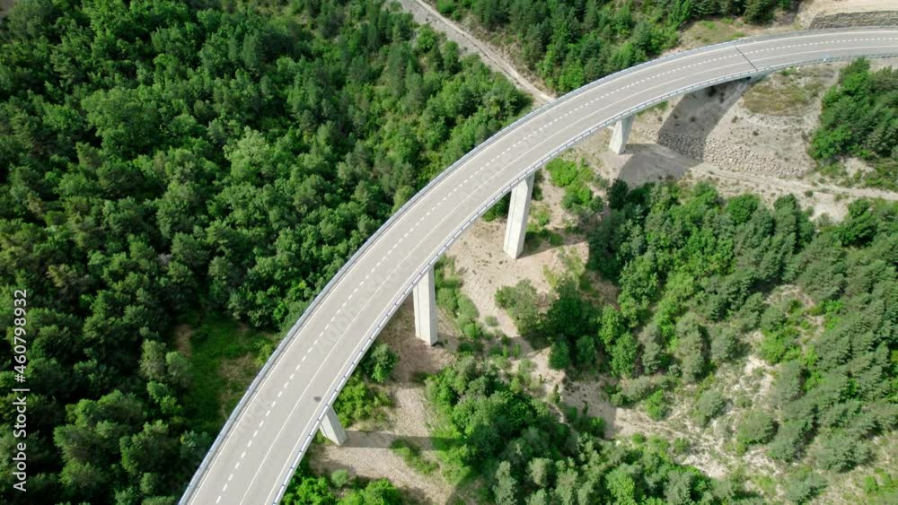 A bridge, a modern viaduct in the mountains with an asphalt road with three lanes. Reinforced concrete wharf structure of the bridge connecting two hills in the mountains covered with forests. A bridge, a modern viaduct in the mountains with an asphalt road with three lanes. Reinforced concrete wharf structure of the bridge connecting two hills in the mountains covered with forests.