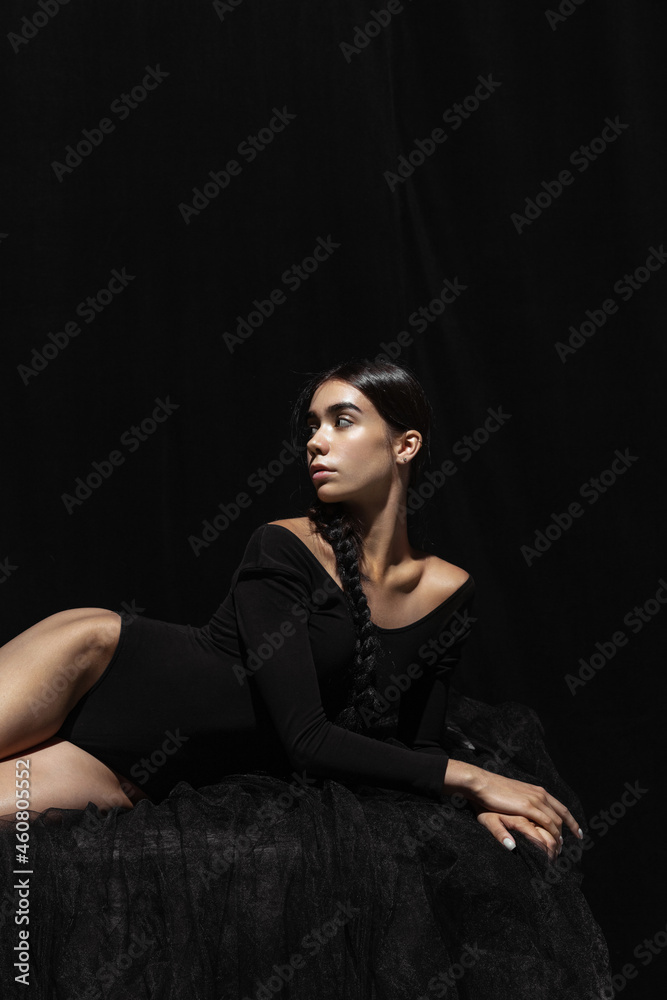 Portrait of young beautiful girl, modern ballet dancers posing isolated on dark background. Feelings, emotions concept Portrait of young beautiful girl, modern ballet dancers posing isolated on dark background. Feelings, emotions concept