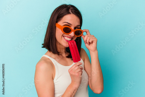 Fotografie Young caucasian woman holding an ice cream isolated on blue background