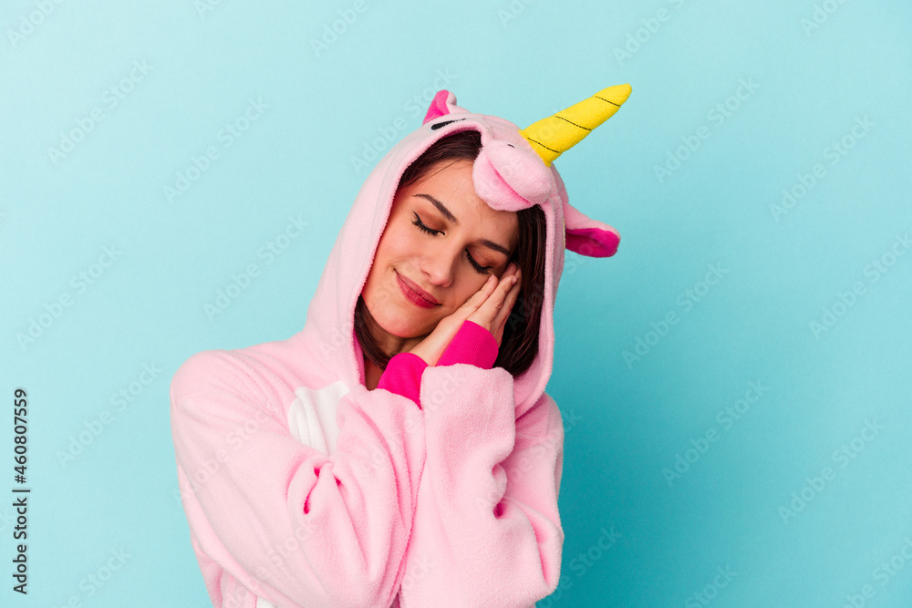Young caucasian woman wearing an unicorn pajama isolated on blue background Young caucasian woman wearing an unicorn pajama isolated on blue background