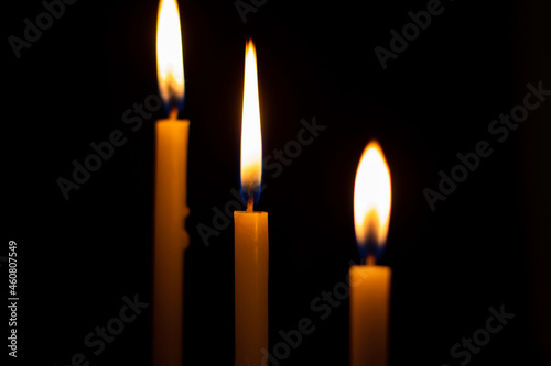Light candle flame blurred background. Light candle a on black background. Prayer with candle in blur hand in the dark