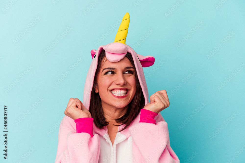 Young caucasian woman wearing an unicorn pajama isolated on blue background Young caucasian woman wearing an unicorn pajama isolated on blue background