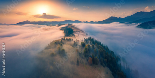 Breathtaking sunrise in Carpathian mountains. Astonishing morning view from fliying drone of the misty valley. Thick fog spreads over the mountain ranges. Beautiful autumn scenery..