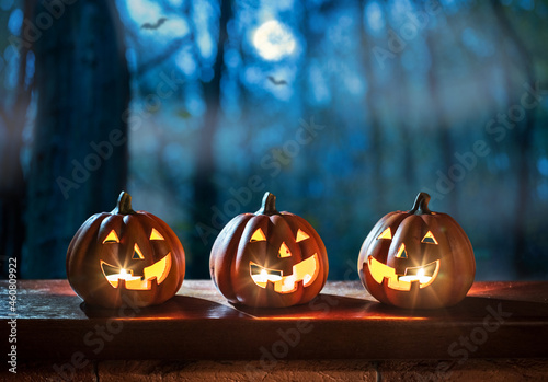 Illuminated Halloween Carved Pumpkins on wooden table. Holiday background. photo