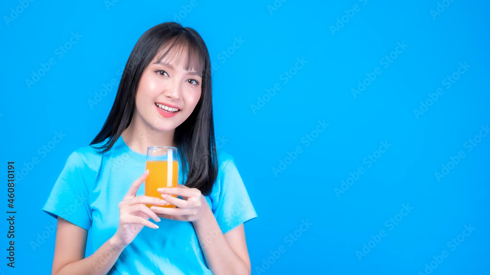 Beautiful beauty Asian woman cute girl with bangs hair style in blue shirt feel happy drinking orange juice for good health on blue background with copy space - lifestyle beauty woman healthy concept Beautiful beauty Asian woman cute girl with bangs hair style in blue shirt feel happy drinking orange juice for good health on blue background with copy space - lifestyle beauty woman healthy concept