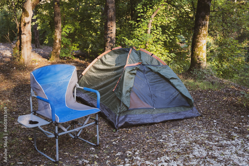 Camping. Tent and chair for rest in the forest. Recreation and relaxation in a peaceful place in nature