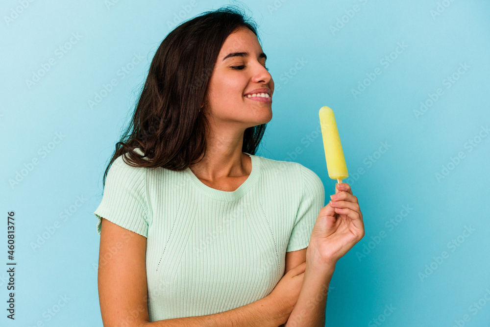 Young caucasian woman holding an ice cream isolated on blue background Young caucasian woman holding an ice cream isolated on blue background
