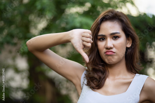 Frowning woman giving rejecting thumb down gesture