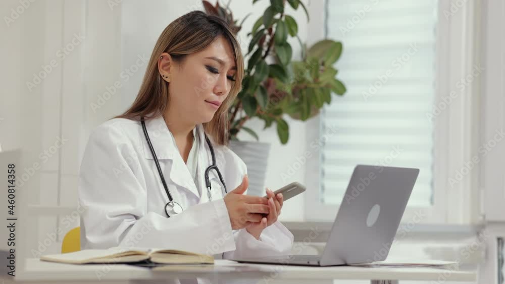Female doctor typing report and talking on phone while sitting at table in clinic office spbi. Beautiful young woman types prescription and looks at computer screen, has mobile call and sits at desk Female doctor typing report and talking on phone while sitting at table in clinic office spbi. Beautiful young woman types prescription and looks at computer screen, has mobile call and sits at desk