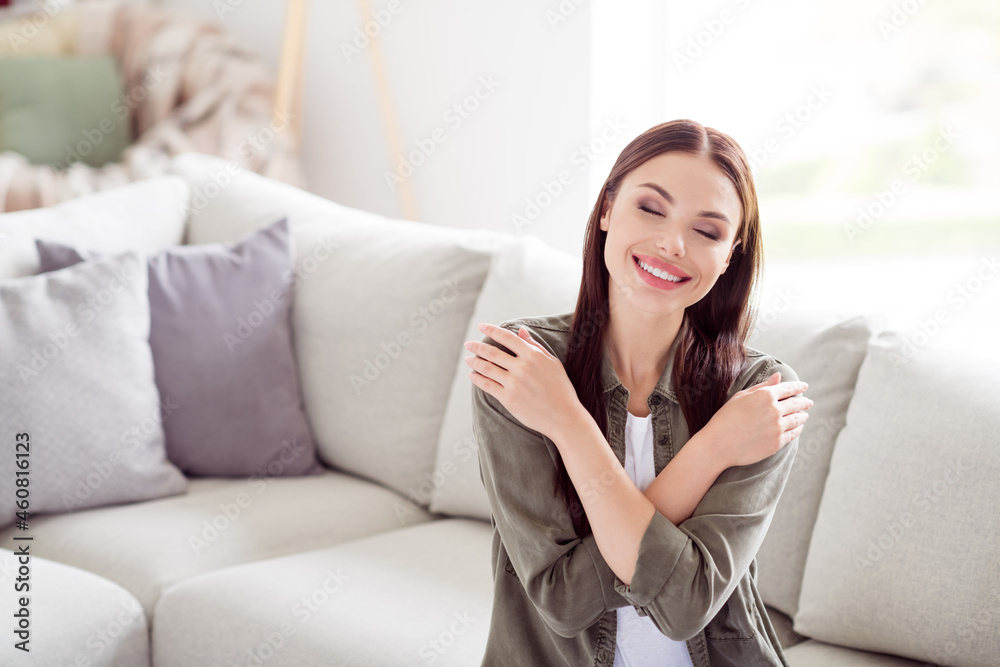 Photo of attractive beautiful young woman dressed khaki shirt hugging herself indoors home room Photo of attractive beautiful young woman dressed khaki shirt hugging herself indoors home room