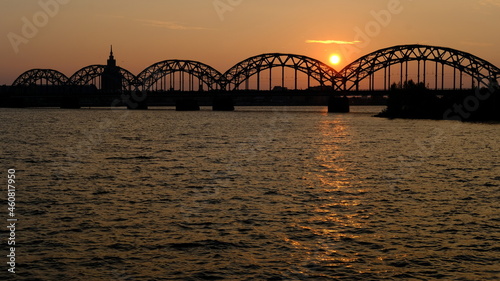 Dawn in Riga, the sun rises over the Daugava river against the background of the railway bridge
