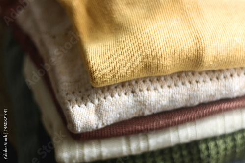 Pile of colorful sweaters in warm tones. Selective focus.