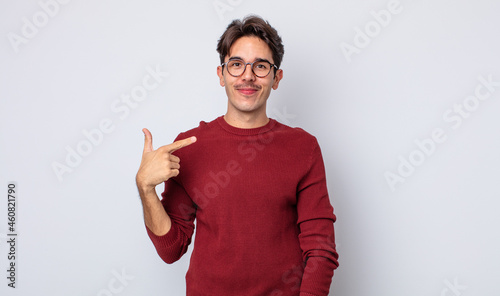 young handsome hispanic man looking proud, confident and happy, smiling and pointing to self or making number one sign