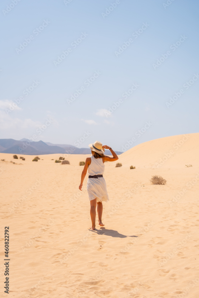 A young tourist wearing a hat walking along the sand on the beaches of the Corralejo Natural Park, Fuerteventura, Canary Islands. Spain