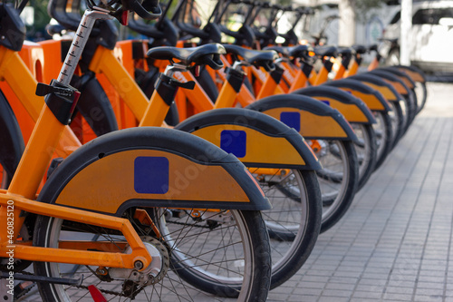 Row of orange bicycles on street parking lot station. Public bike rental in urban city concept