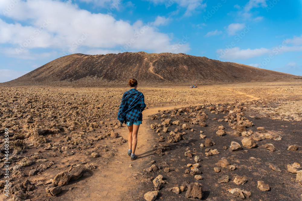 A young woman on the trail to the Crater of the Calderon Hondo volcano near Corralejo, north coast of the island of Fuerteventura, Canary Islands. Spain