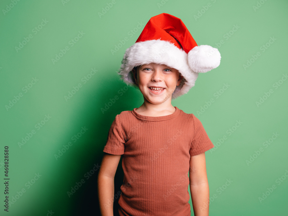 Smiling boy wearing Santa Claus hat standing in studio Smiling boy wearing Santa Claus hat standing in studio
