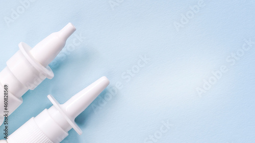 2 white nasal sprays on a light blue background. The concept of autumn diseases, allergies. photo