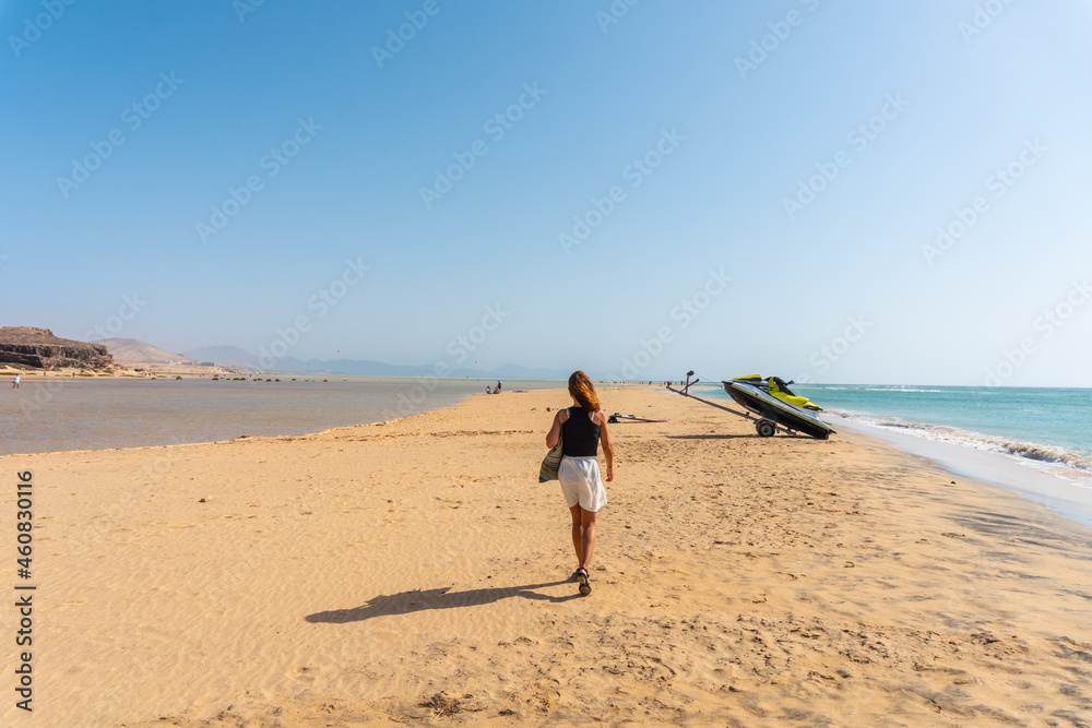 A young tourist walking along the Sotavento beach in the south of Fuerteventura, Canary Islands. Spain