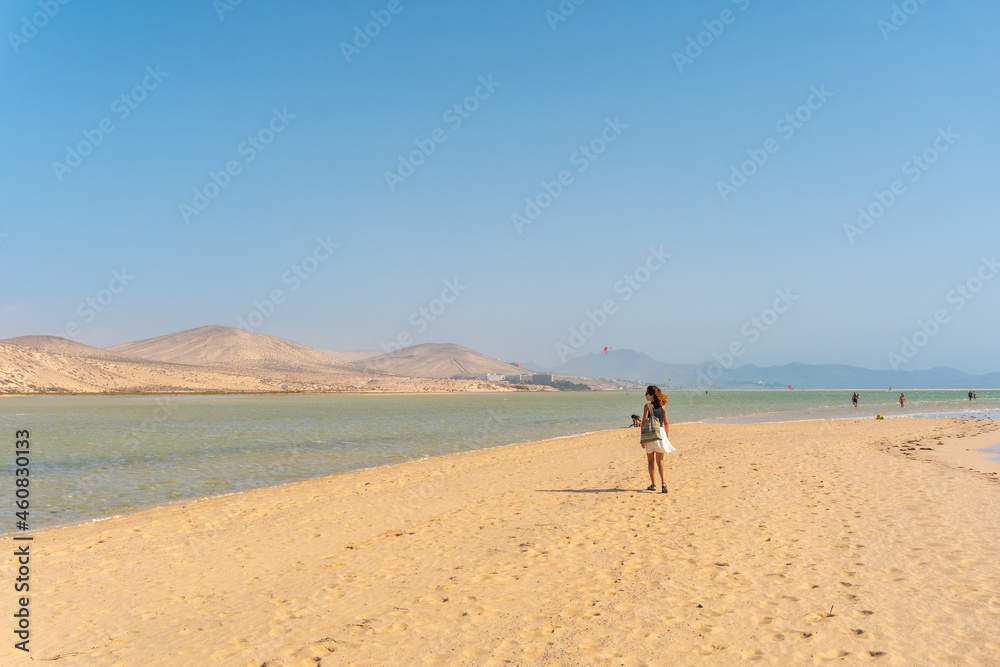 A young tourist walking along the Sotavento beach one autumn morning in the south of Fuerteventura, Canary Islands. Spain
