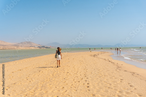 A young tourist walking along the Sotavento beach in the south of Fuerteventura, Canary Islands. Spain