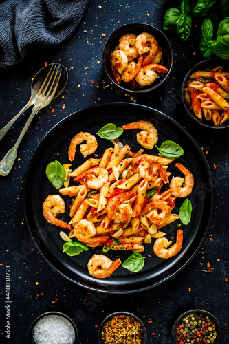 Penne with fried prawns in on black wooden background 