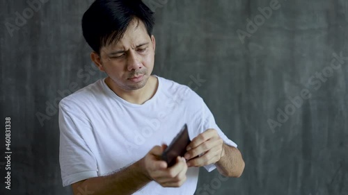 asian man opening wallet looking for money with shocked face unhappy