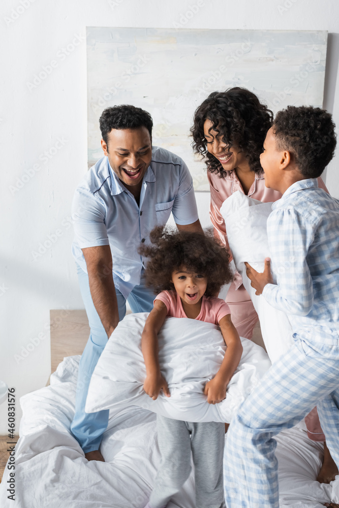 excited african american family in pajamas having fun with pillows in bedroom excited african american family in pajamas having fun with pillows in bedroom