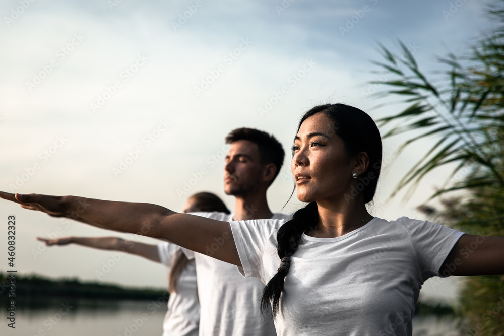 Group of people doing yoga exercises by the lake at sunset. Group of people doing yoga exercises by the lake at sunset.