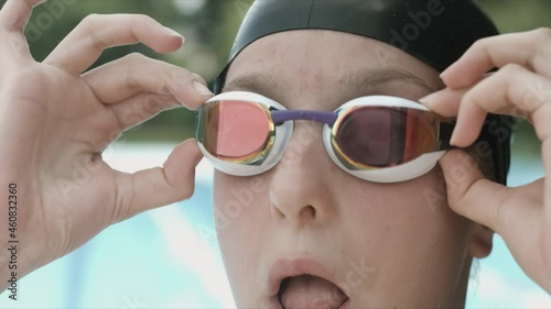 Extreme close-up shot of a Caucasian girl�s head with a swimming cap and hands putting swimming goggles, preparing for training in the pool. photo