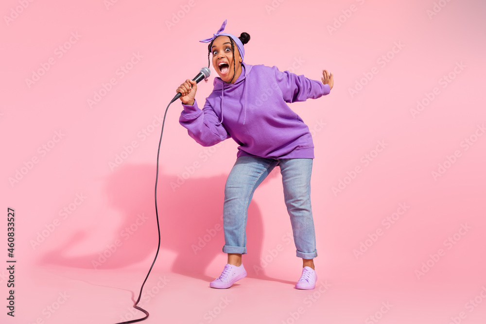 Photo of pretty shiny african lady dressed violet sweatshirt buns smiling singing songs isolated pink color background